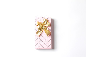 Pink gift box with a large gold bow. White background. Holiday concept, flat lay, top view