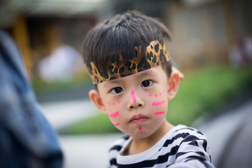 A little boy getting his face painted like a tiger