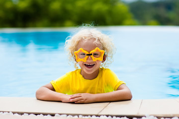 Child with goggles in swimming pool. Kids swim.