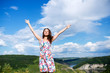 A relaxed girl stands by spreading her arms in front of the horizon