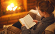 © JenkoAtaman - young woman   reading a book by the fireplace on a winter evening.
