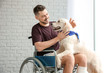 Man in wheelchair with service dog indoors