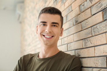 Canvas Print - Portrait of young man in casual clothes near brick wall