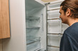 © DedMityay - Hungry man looks for food in empty fridge