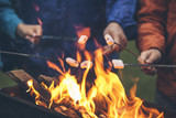 Fototapeta  - Hands of friends roasting marshmallows over the fire in a grill closeup