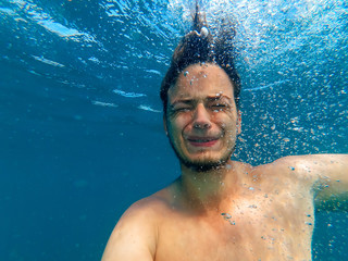 man under water, drowning with an expression of fear and horror on her face