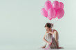 © LIGHTFIELD STUDIOS - ballet dancer in white dress sitting with pink balloons, isolated on white