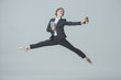 © LIGHTFIELD STUDIOS - businesswoman in suit and ballet shoes jumping with coffee and tablet, isolated on grey