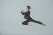 © LIGHTFIELD STUDIOS - businesswoman in suit and ballet shoes jumping and using digital tablet, isolated on grey