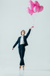 © LIGHTFIELD STUDIOS - businesswoman in suit and ballet shoes holding pink balloons, isolated on grey