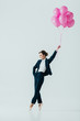 © LIGHTFIELD STUDIOS - businesswoman in suit and ballet shoes with pink balloons, isolated on grey