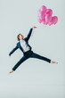 © LIGHTFIELD STUDIOS - businesswoman in suit and ballet shoes jumping with pink balloons, isolated on grey