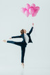 © LIGHTFIELD STUDIOS - businesswoman in suit and ballet shoes holding pink balloons, isolated on grey