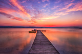 Fototapeta Zachód słońca - Exciting sunset at shore with wooden pier and boat