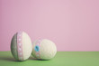 Easter still life with decorative easter eggs in pastel colours on the pink and green background