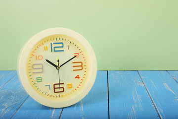 Wall Mural - Retro alarm clock on a wood and green background