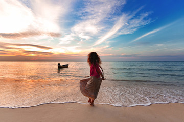 Wall Mural - Cheerful young woman having fun on the beach at sunset