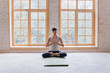 © yuliyalyashok - Relaxed young man doing yoga and meditating in studio