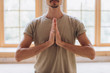 © yuliyalyashok - Relaxed young man doing yoga and meditating in studio
