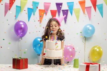 Little girl blowing candles on a birthday cake