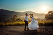 Emotional wedding shot of the happy glamour newlywed couple dancing on the road during the sunset. Beautiful nature view.