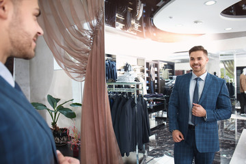 Canvas Print - Handsome young man wearing suit looking in mirror at store