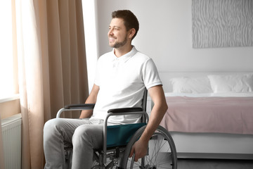 Canvas Print - Young man in wheelchair near window indoors