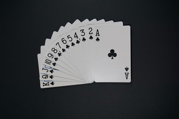 Full club series of playing cards on black surface