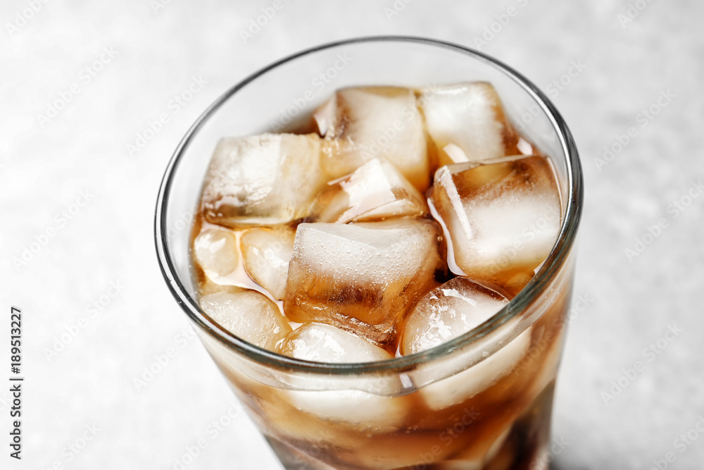 Cold cola in glass on light background, closeup