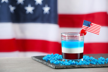 Layered cocktail in colors of American flag on table against blurred background