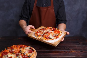 Chef with freshly baked pizza in hands. Cooking process, Italian food concept