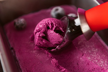 pink ice cream with a spatula for ice cream on a dark wooden background with waffle cups