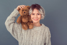 Young Woman In A Woolen Sweater Isolated On Grey Wall Winter Concept Holding Teddy Bear