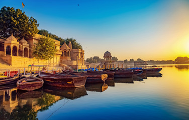 Fototapete - Gadisar lake (Gadi Sagar) Jaisalmer Rajasthan with ancient architecture and tourist boats at sunrise