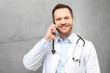 Lekarz rozmawia przez telefon.
Przystojny lekarz ubrany w biały kitel stoi w klinice i rozmawia przez telefon
