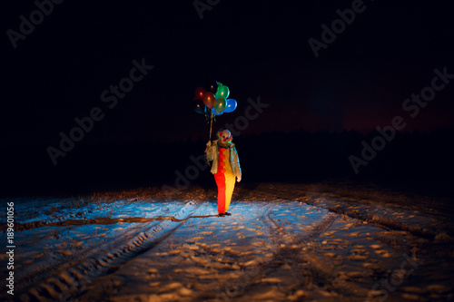 Fotografía Full-length clown photo with colorful balloons at night