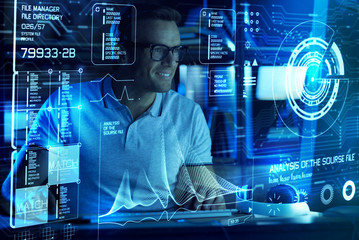 Ready to detect. Cheerful professional IT man smiling and coding while being involved in work