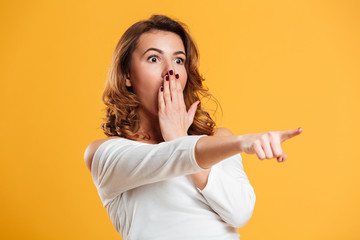 Wall Mural - Shocked young woman pointing.