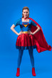 © LIGHTFIELD STUDIOS - beautiful confident woman in superhero costume standing akimbo isolated on blue