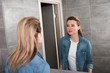 © LIGHTFIELD STUDIOS - attractive woman in casual clothing looking in mirror at home