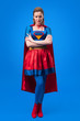 © LIGHTFIELD STUDIOS - attractive woman in superhero costume with arms crossed isolated on blue