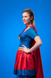 © LIGHTFIELD STUDIOS - side view of beautiful woman in superhero costume standing akimbo isolated on blue