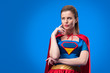 © LIGHTFIELD STUDIOS - portrait of pensive woman in superhero costume looking away isolated on blue