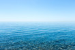 Beautiful seascape with a view of the horizon and a cloudless sky. Small smooth stones lying on the sea bottom with clear water on the shore