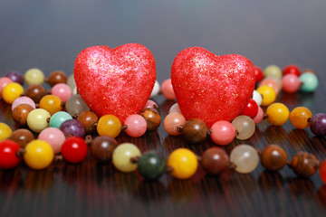 Two decorative hearts among colorful beads on dark background