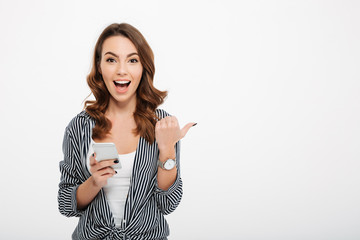 Wall Mural - Portrait of a cheerful casual girl holding mobile phone