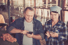 Senior Man And Female Farmers Using Phones On Farm