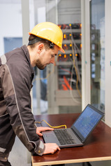 Wall Mural - maintenance engineer inspect relay protection system with laptop computer