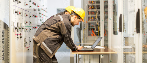 Cuadros en Lienzo Two maintenance engineers inspect relay protection system with laptop comp