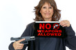 © Pamela Au - Middle Aged Woman holding a No Weapons Sign and a Handgun